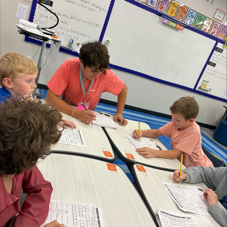 middle school student works with elementary students