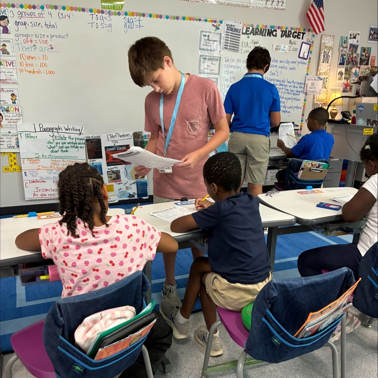 middle school student works with elementary students