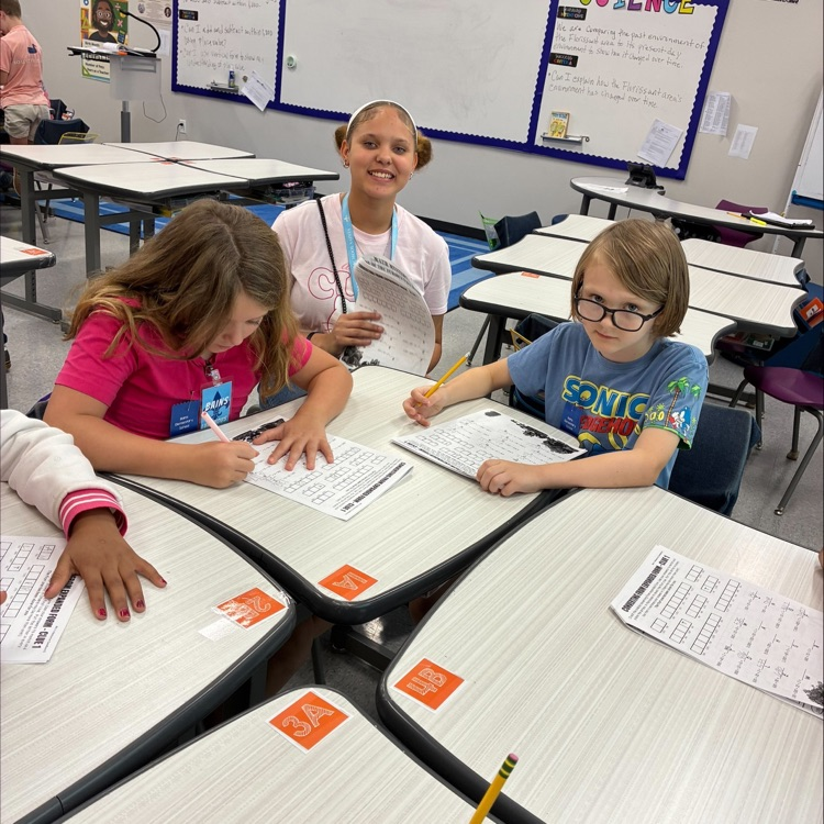 middle school student works with elementary students