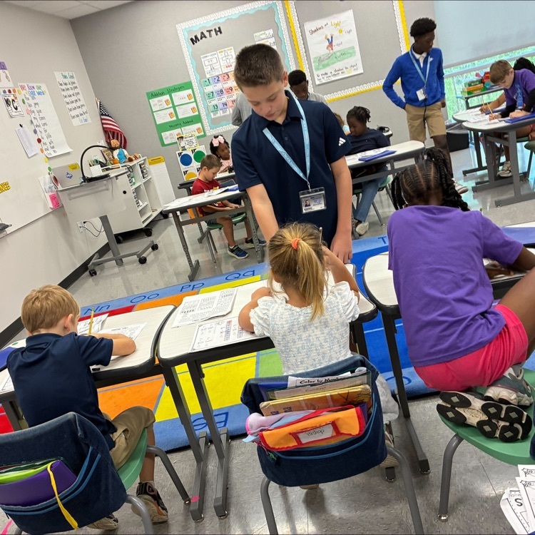 middle school student works with elementary students