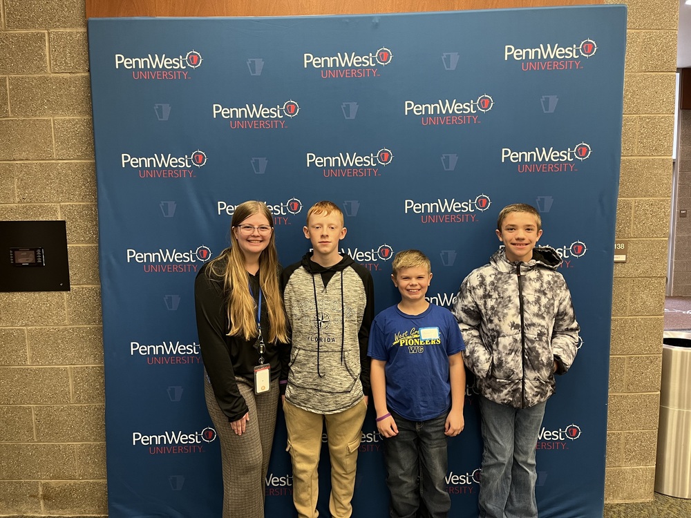 Miss Nulph is pictured next to three 5th grade students at Penn West University