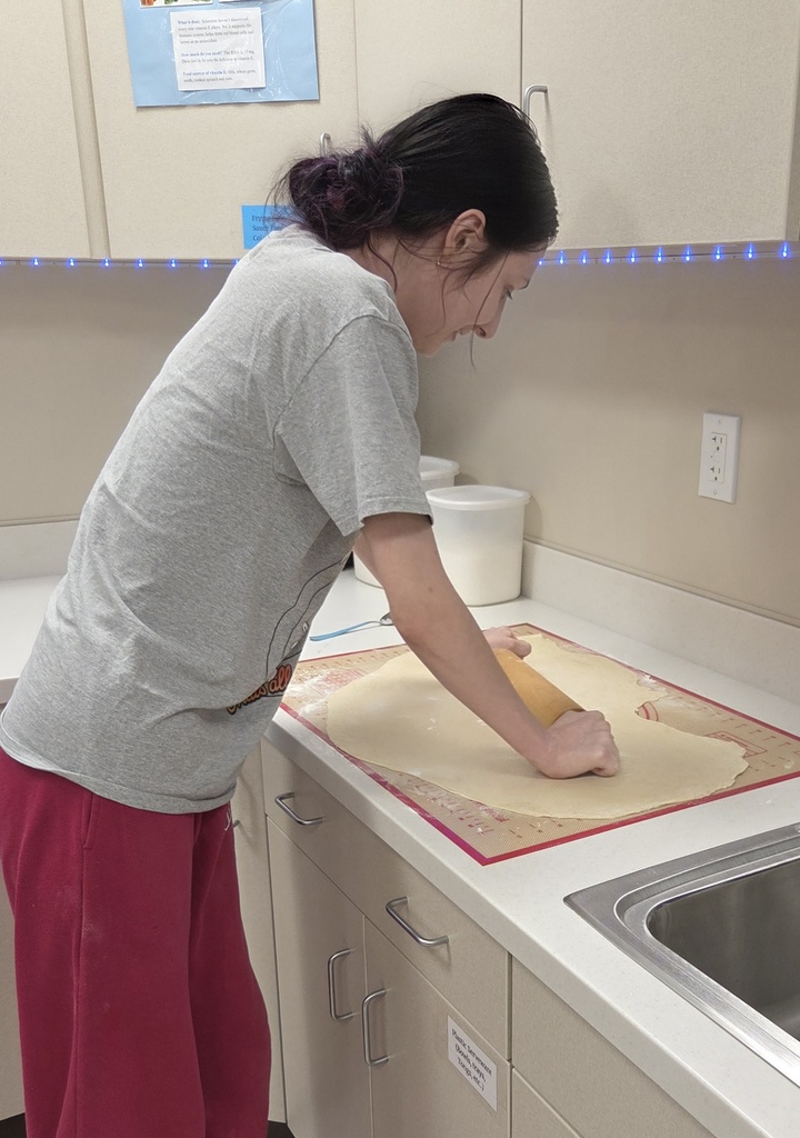 A student rolls dough.
