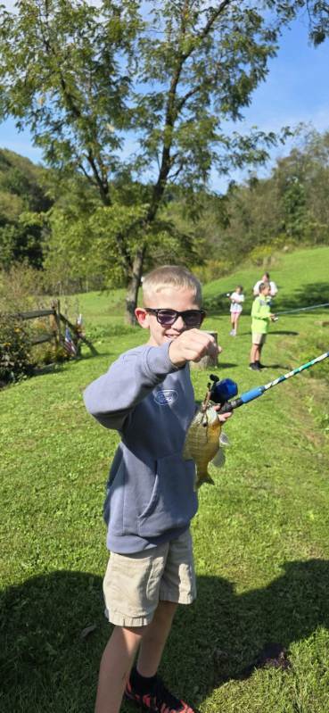 A student in Mrs. Rohrer's classroom shows a fish he caught at Blessed Valley Lodging.