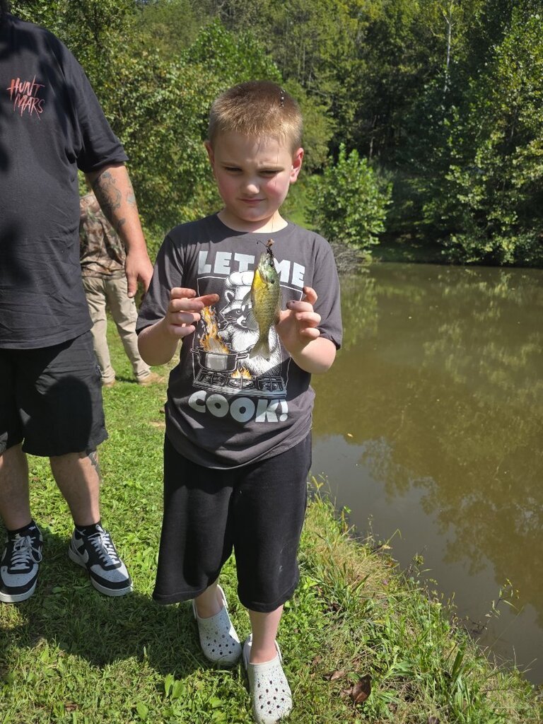 A student in Mrs. Rohrer's classroom shows a fish he caught at Blessed Valley Lodging.