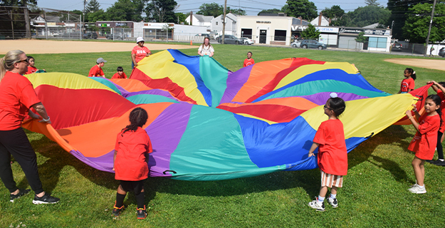 Students and teachers holding large parachute.