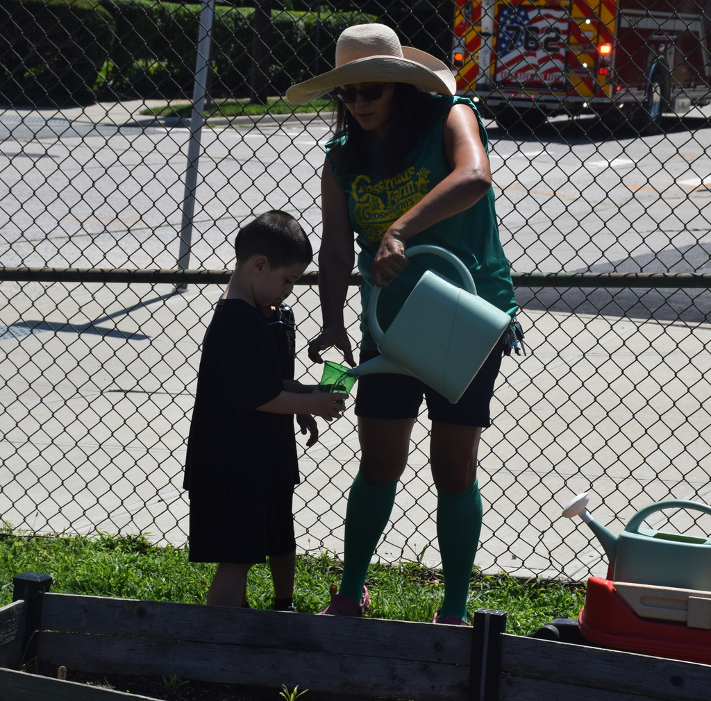 Photo of student receiving water for garden from gardener.