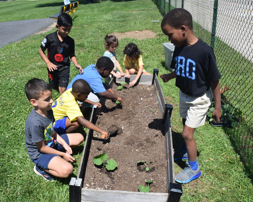 Photo of students gardening near playground.