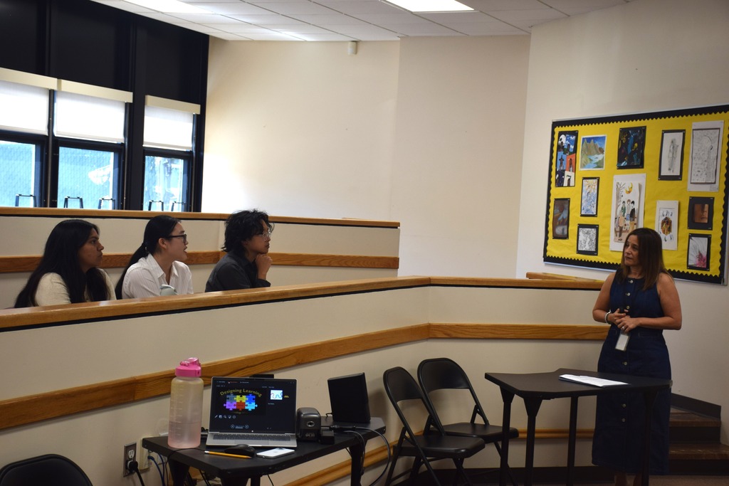 Photo of three Teacher Residency Program scholars sitting while listening to West Hempstead's assistant superintendent.