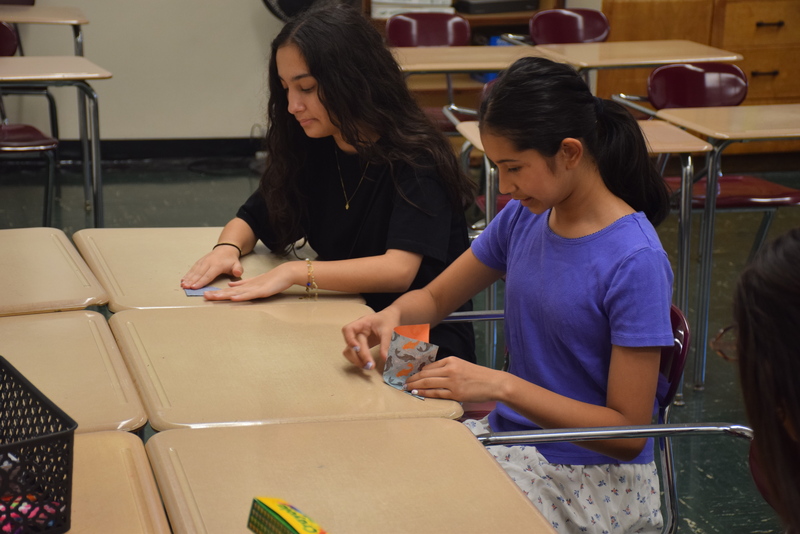 students folding shapes in classroom during STEAM Night.