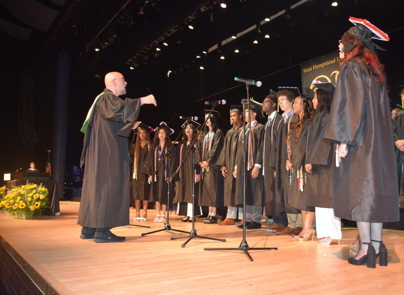 graduates in cap and gowns on stage