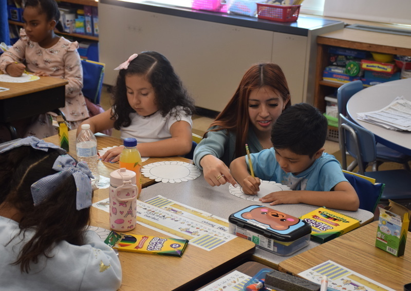 Students coloring at classroom tables