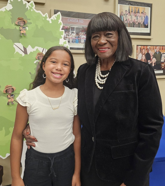 student stands beside older woman