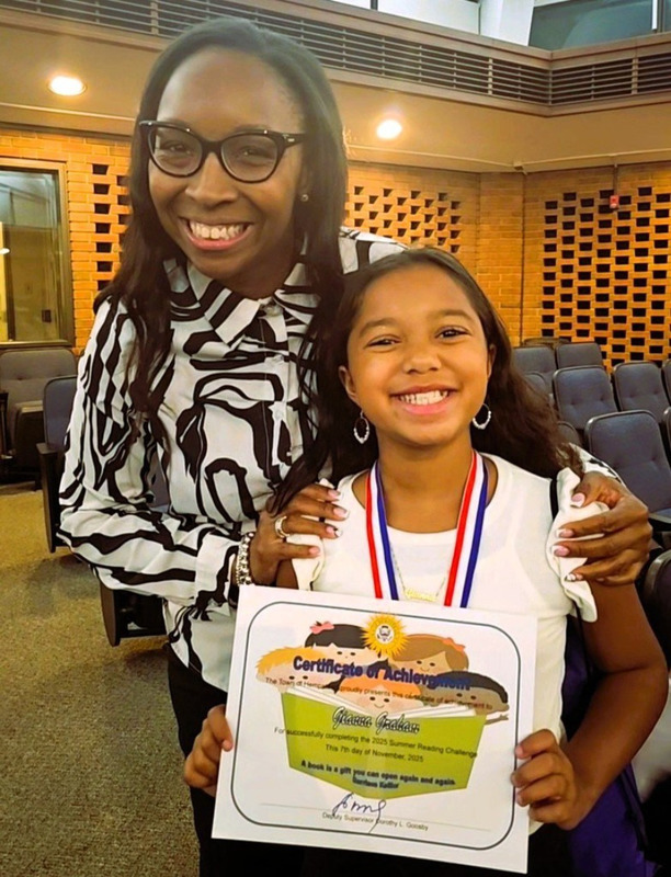 student stands beside older woman showing certificate
