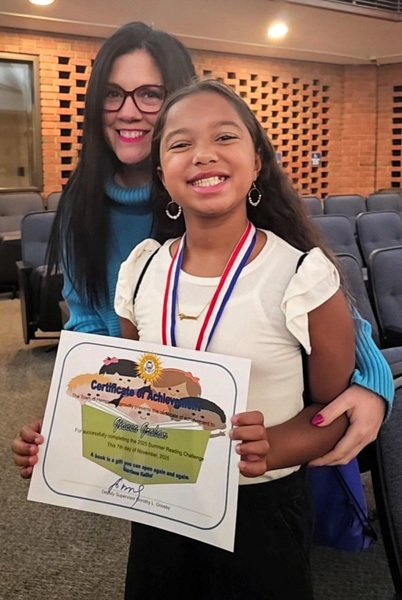 student stands beside older woman showing certificate