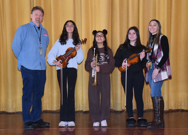people stand in a line on a stage with red curtains. They appear confident and composed, suggesting a formal or celebratory event.