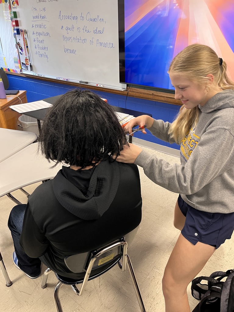 Students giving a haircut to a wig in study hall.