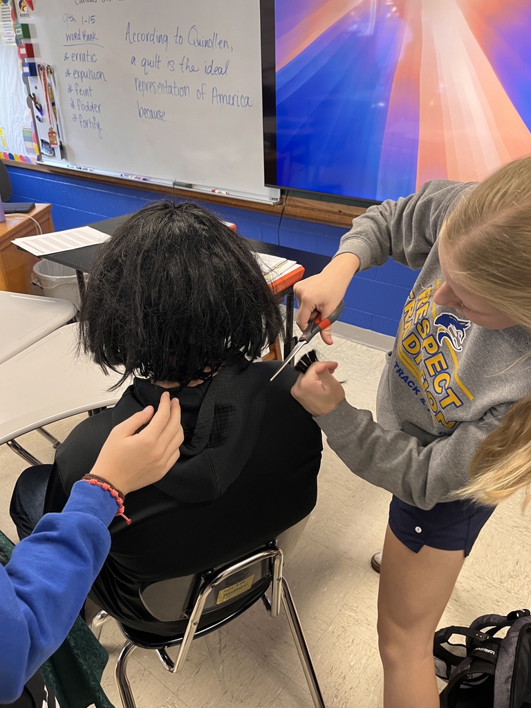 Students giving a haircut to a wig in study hall.
