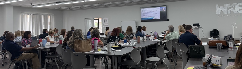 people in a room at wkec listening to a speaker