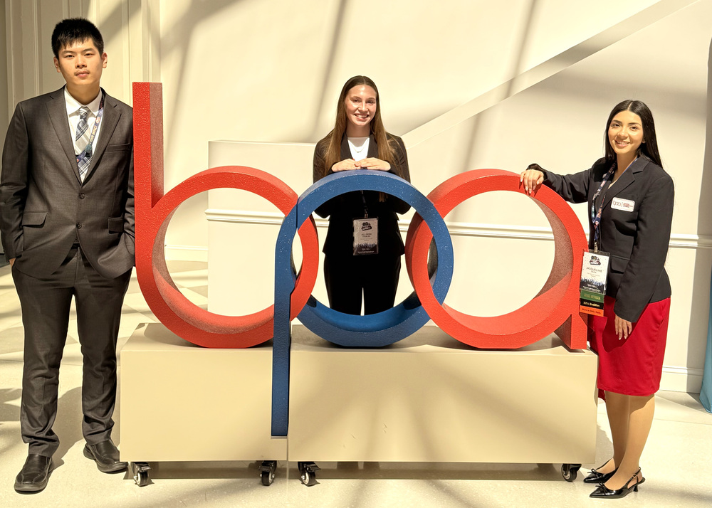 three people by a bpa sign at a conference