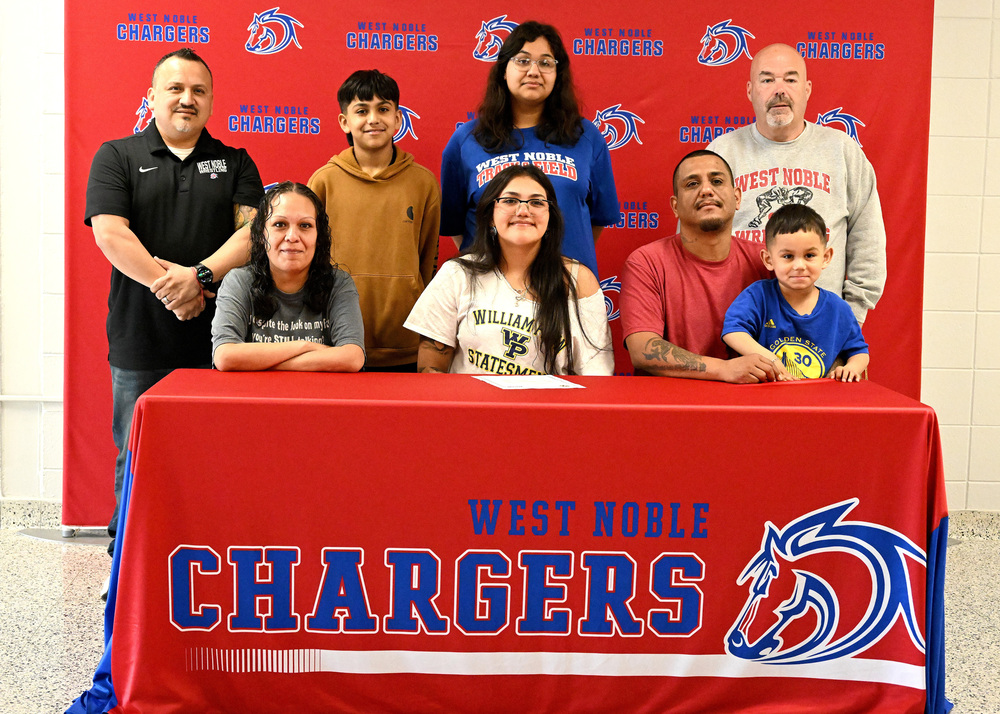 eight people sitting at a table at a college signing