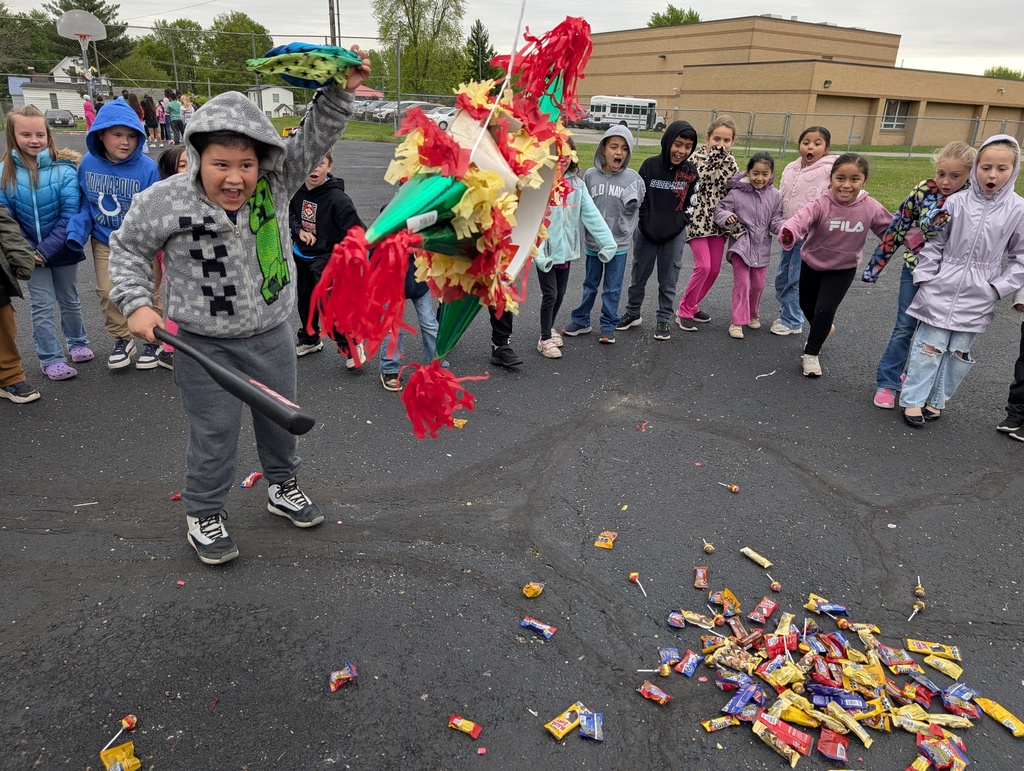 a young boy hitting a pinata with candy falling out