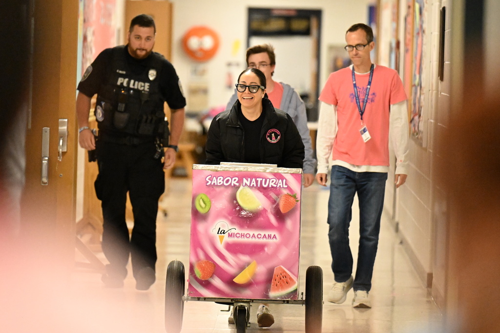 a lady pushing an ice cream cart escorted by top men