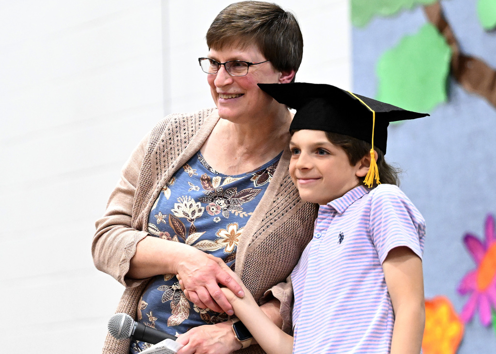 a young boy posing for pictures with his teacher