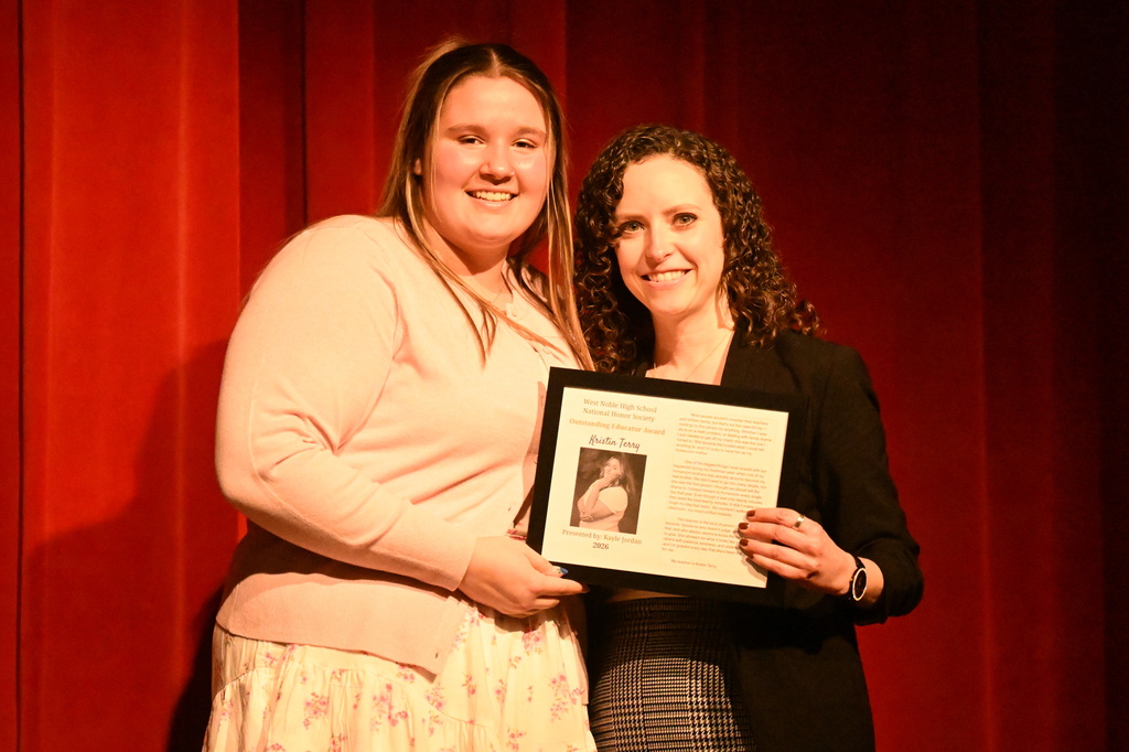 two women on a stage with an award