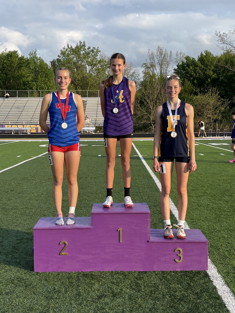 three girls standing on a podium at a track meet
