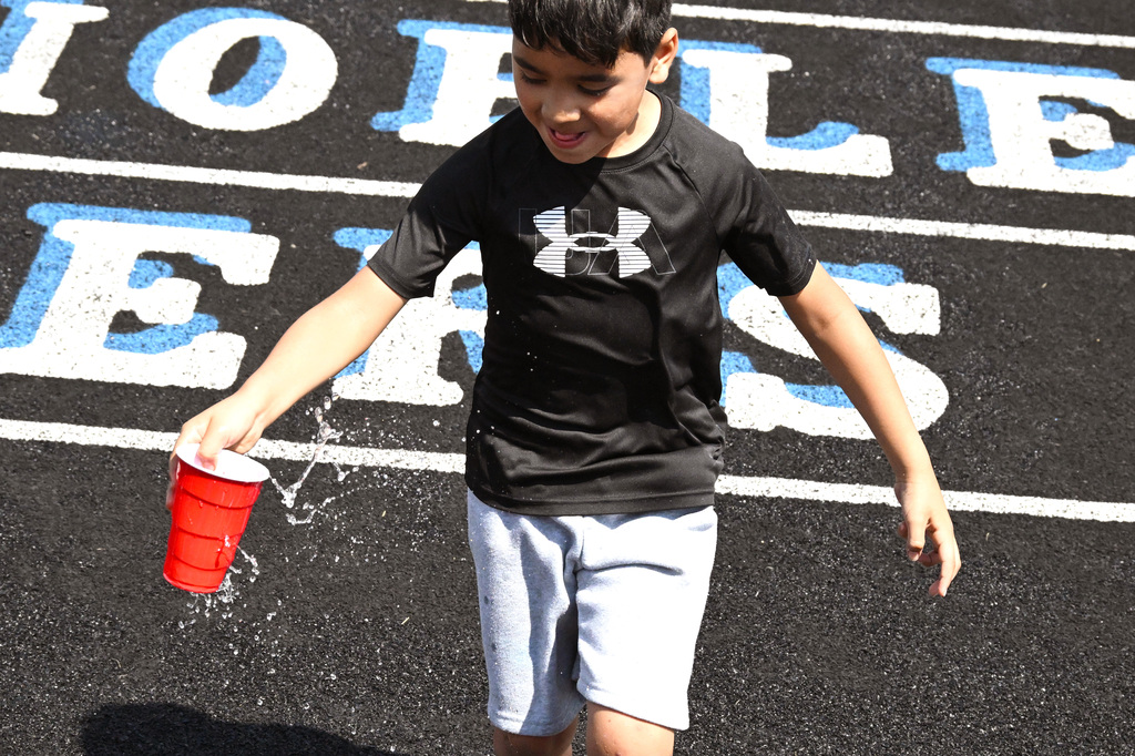 a boy carrying a cup of water that's splashing