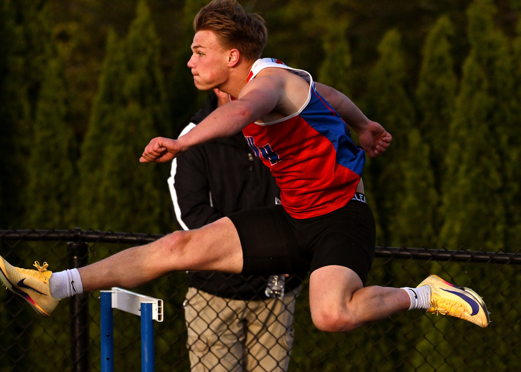 track athlete jumping over a hurdle