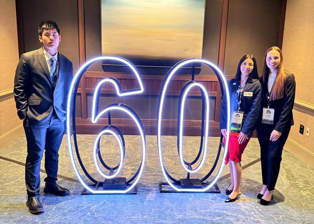 three people by a 60 neon sign