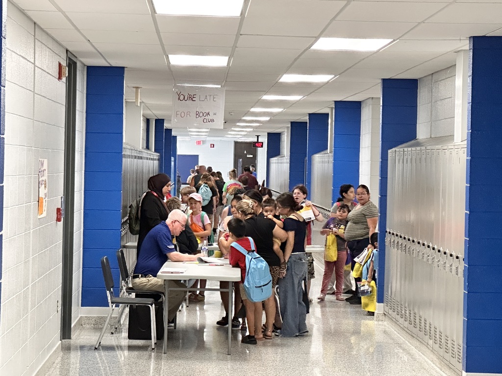 a group of people standing near tables at a back to school event