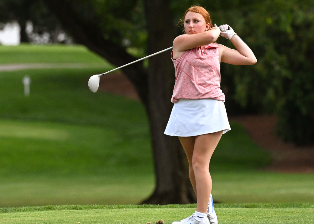 a girl in pink and white golfing