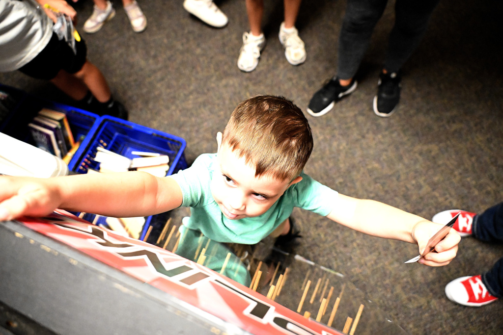 a boy in a green shirt reaching up to touch a sign