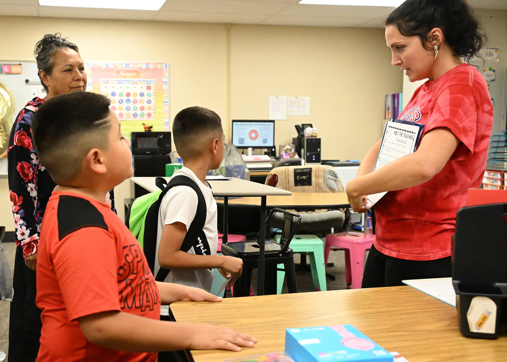 a teacher in a red shirt talking to a student in a white shirt
