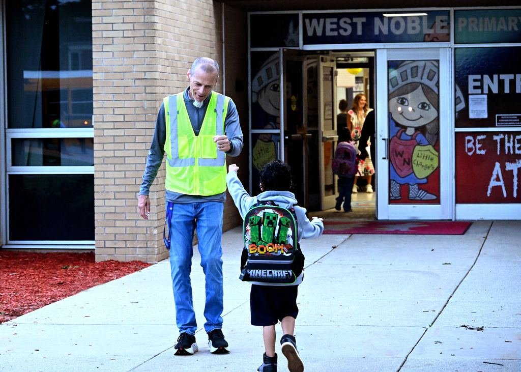 a principal fist bumps a student walking into a school