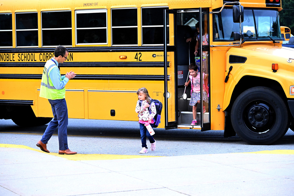 a teacher greets students getting off a school bus