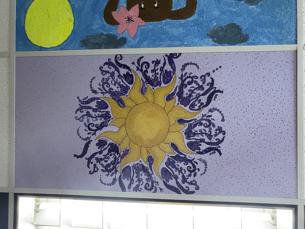 a sun drawing on a ceiling tile