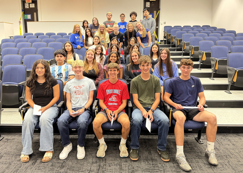 a group of students sitting in the blue seats