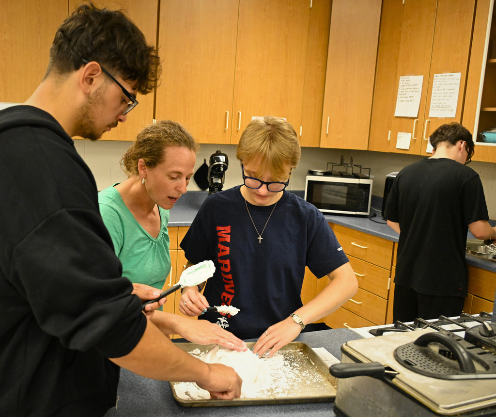 three people cooking in a kitchen