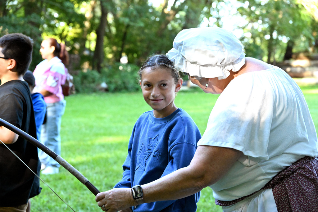 a girl in blue looking at a woman with a bow