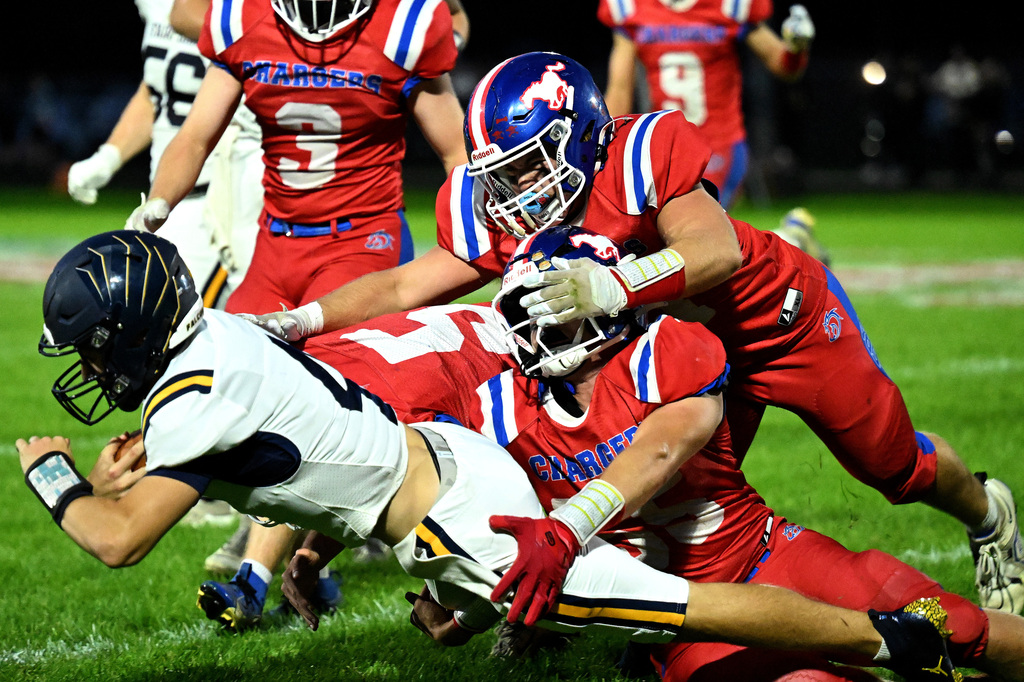 three football players in red tackling a player in white