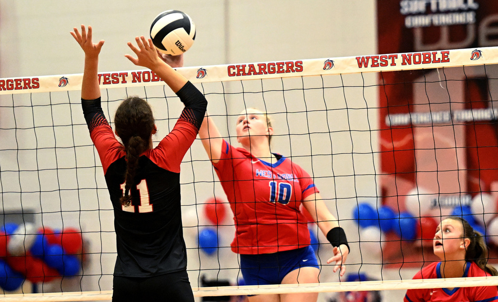 a volleyball player tipping a ball over the net