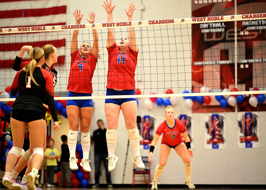two girls trying to block a volleyball