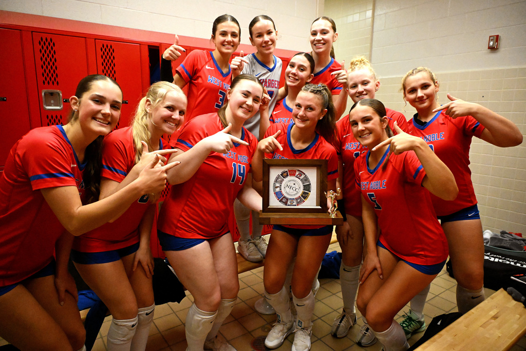 volleyball players posing with a trophy