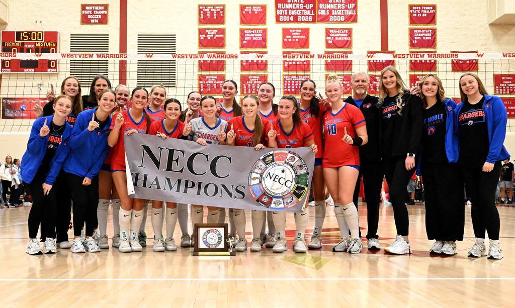a volleyball team posing with a trophy and a banner