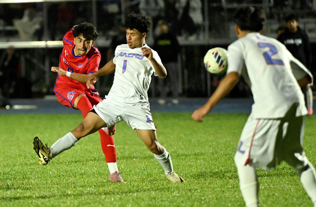 soccer player kicking a ball past a player