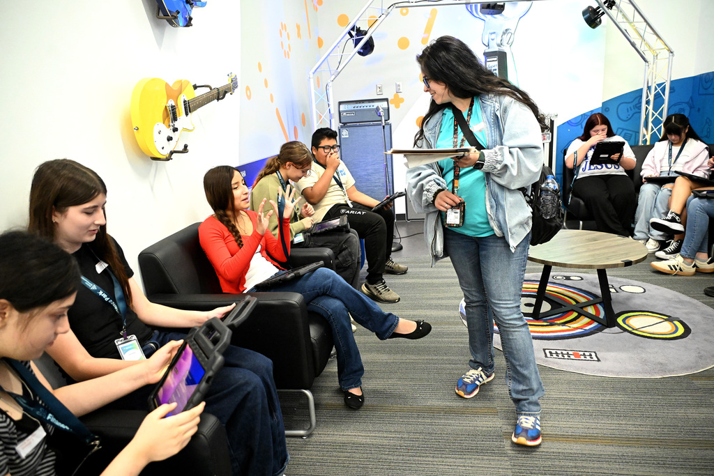 A student and a teacher talking with others working on tablets