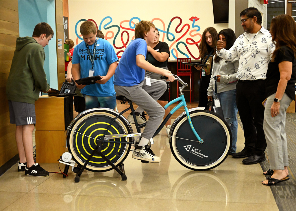 A student riding on a bike with onlookers